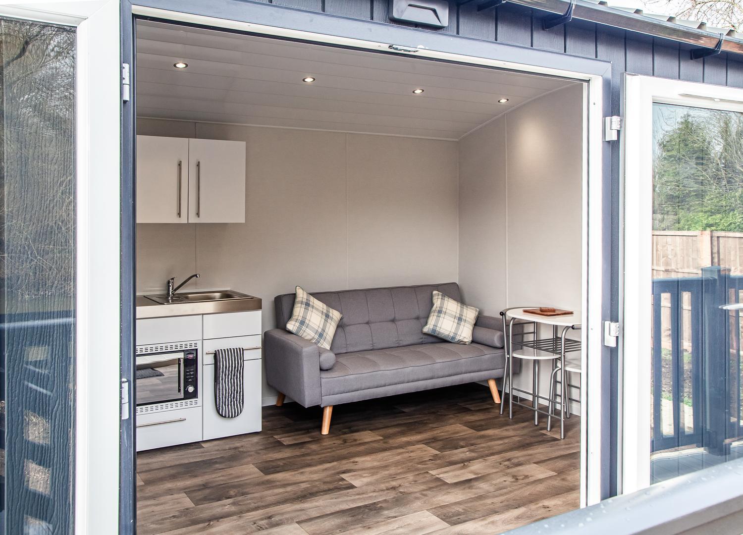 Double doors into holiday accommodation - small kitchenette and grey sofa can be seen through the doors