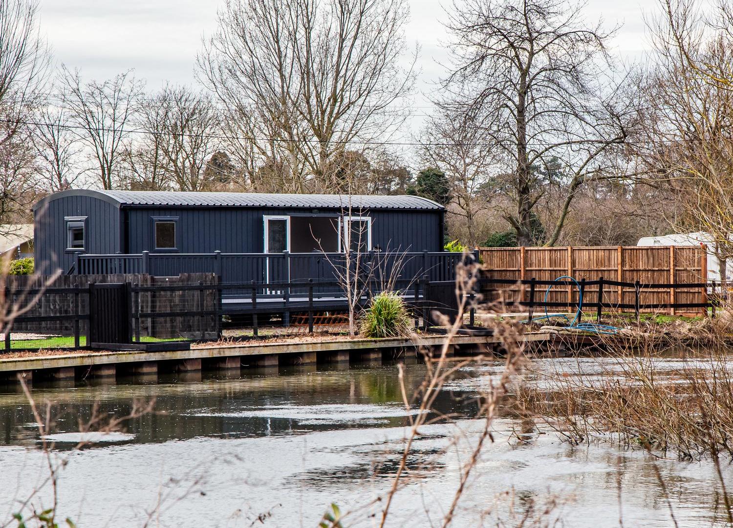 Grey shepherds hut style holiday accommodation next to river